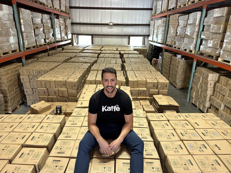 Robert Gomez sitting on pallets of Kaffe stock in the company warehouse